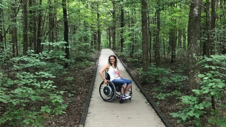 Arlene en fauteuil roulant sur un sentier dans les bois